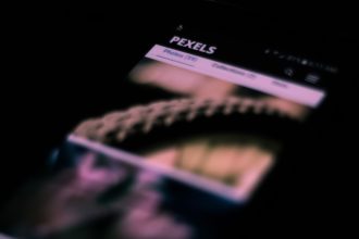 Smartphone em close com imagens e textos desfocados na tela, remetendo a uma interface de rede social.